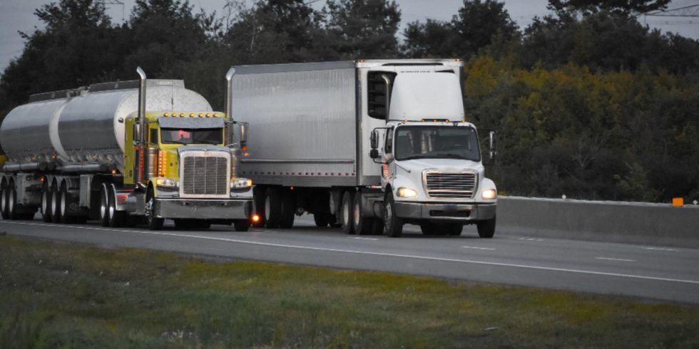 Two white truck traveling on road to another state