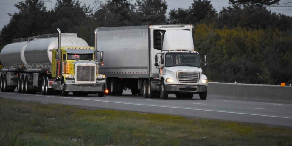 Two white truck traveling on road to another state and it is one of the best roads for truck drivers.